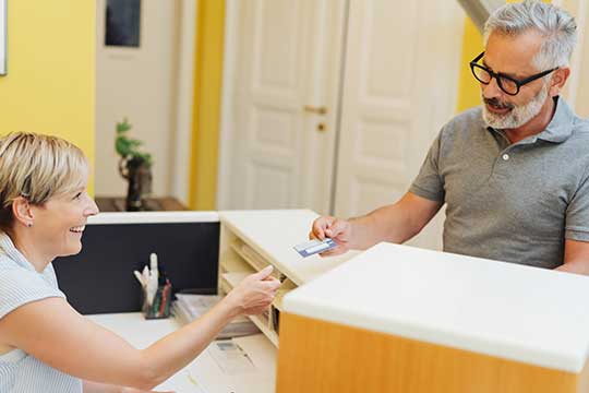 Man handing over credit card to pay for hearing aids 