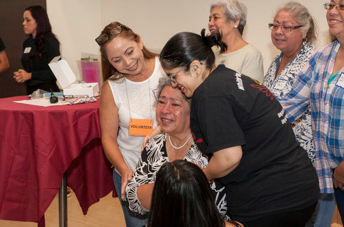 Volunteers embracing a patient happy to receive hearing aids