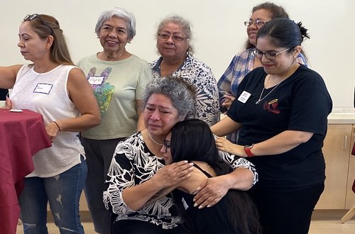 Volunteers embracing a patient happy to receive hearing aids