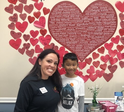 Audiologist with a  child in front of a display of hearts on the wall